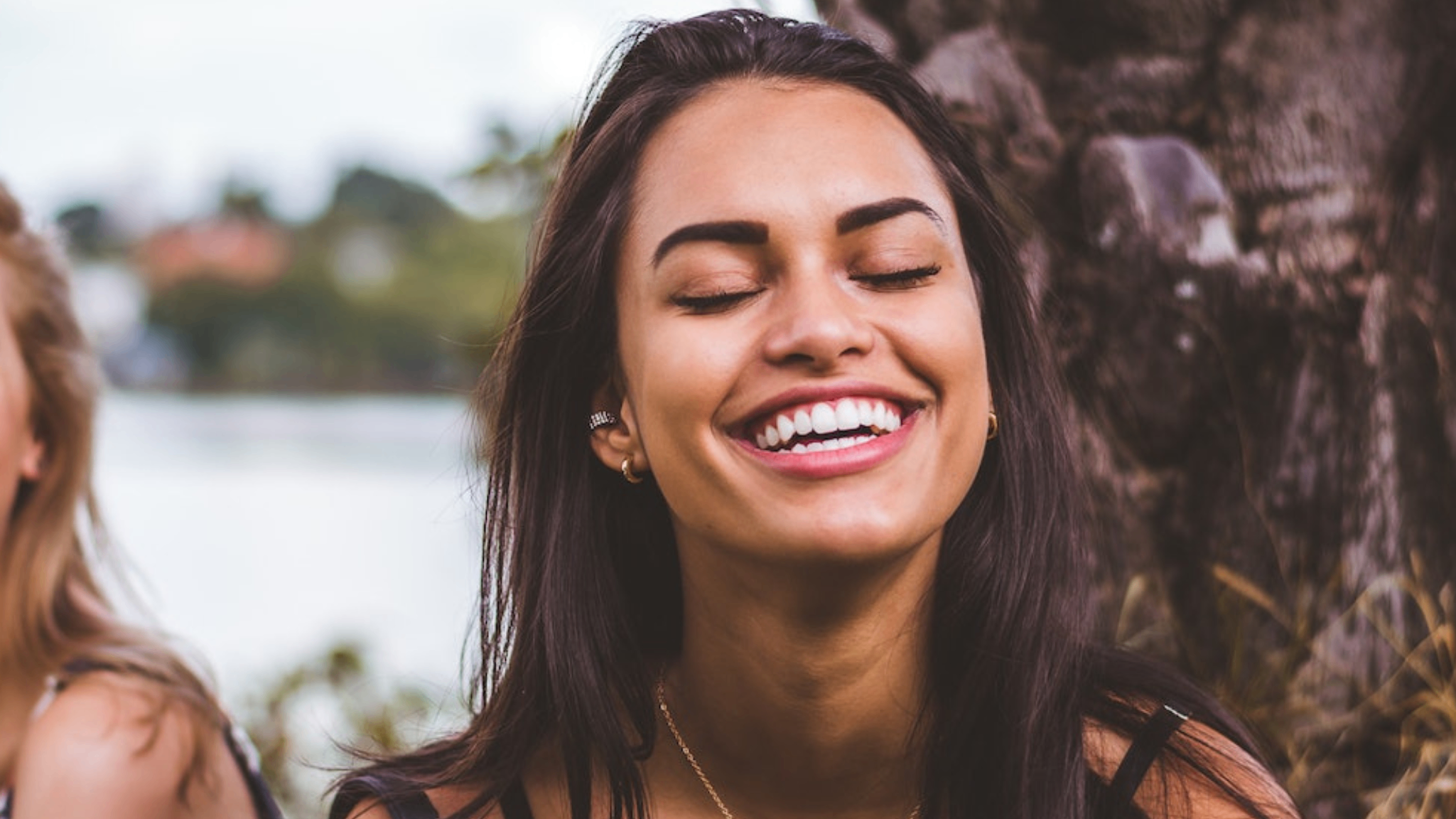 girl with bright white teeth smiling  with her eyes closed