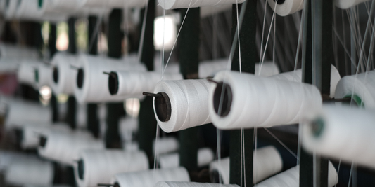 Multiple white yarn spools sitting at a manufacture 