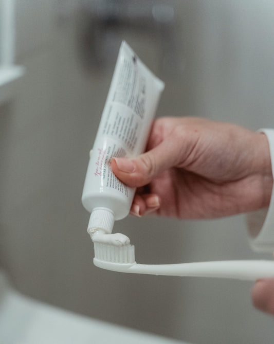 White plastic toothbrush getting toothpaste on it | Vearthy Canada