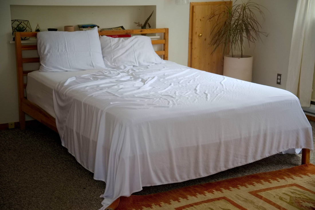 White bamboo lyocell bedding hangs off corner of wood framed bed Vearthy