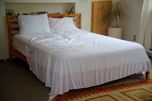 White bamboo lyocell bedding hangs off corner of wood framed bed Vearthy