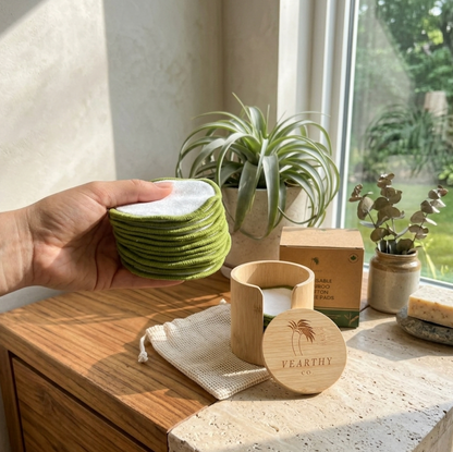 Hand holding reusable bamboo cotton round face pads, with a bamboo Vearthy container on the counter in the background. 