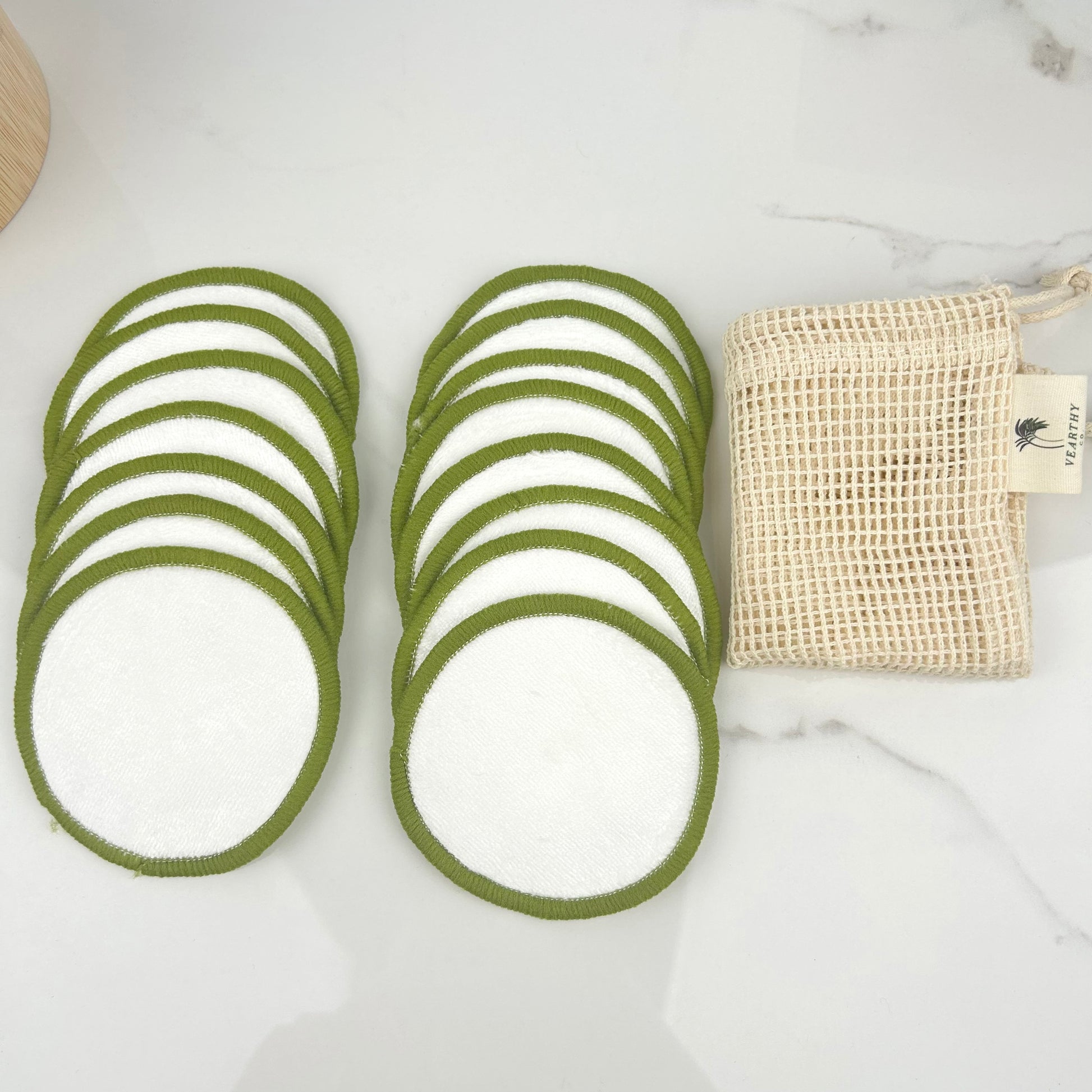 Set of green circular face pads with a beige laundry pouch on a white surface