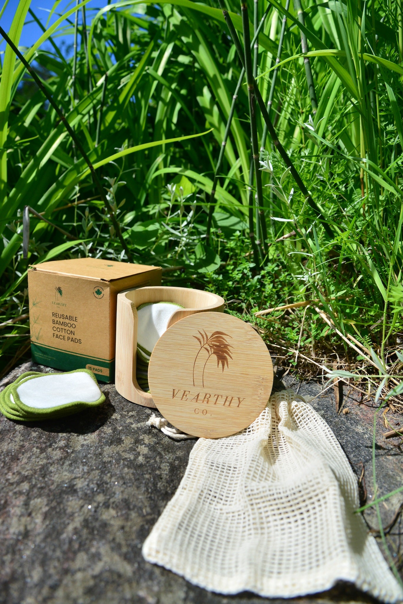 Vearthy reusable bamboo cotton face pads  sitting on a rock with packaging and accessories 