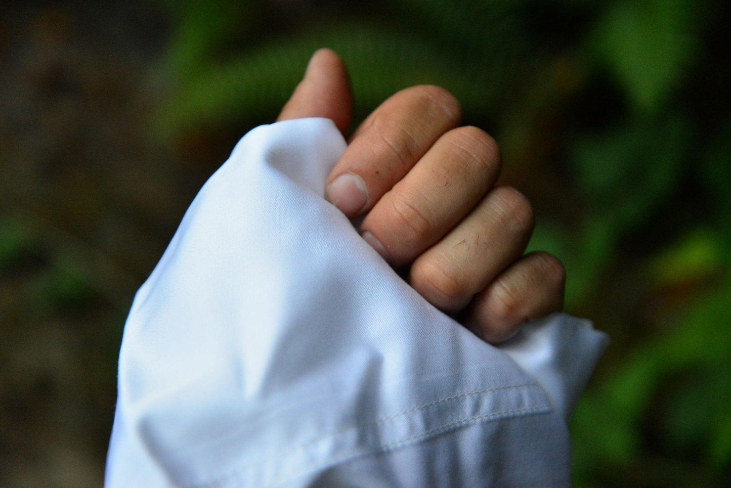 A hand holding silky white bamboo sheet. You can see how soft it looks against the skin.